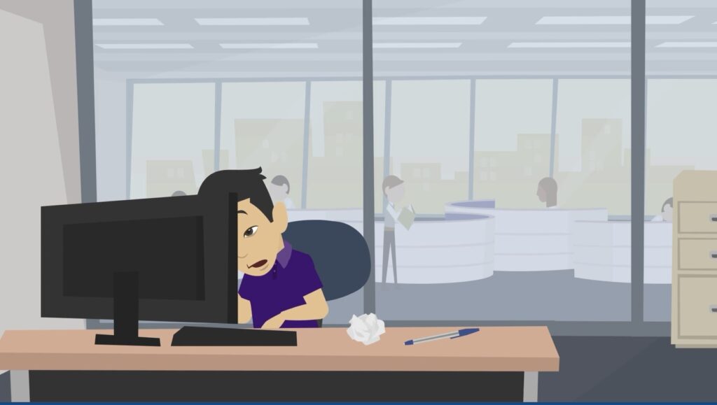 Muž v kanclu se dívá do počítače a sleduje filmy pro dospělé. V pozadí pracují jeho kolegové.